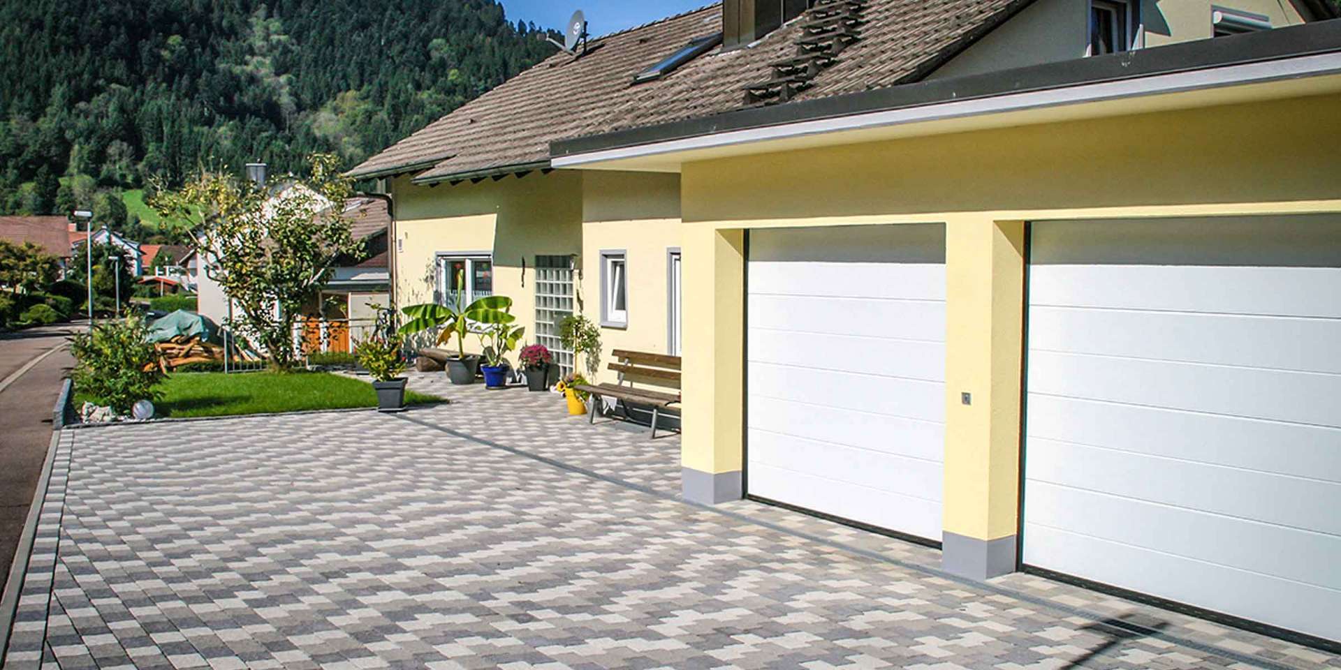 Gepflasterte Außenanlage mit Natursteinmauer von Vollmer Bau